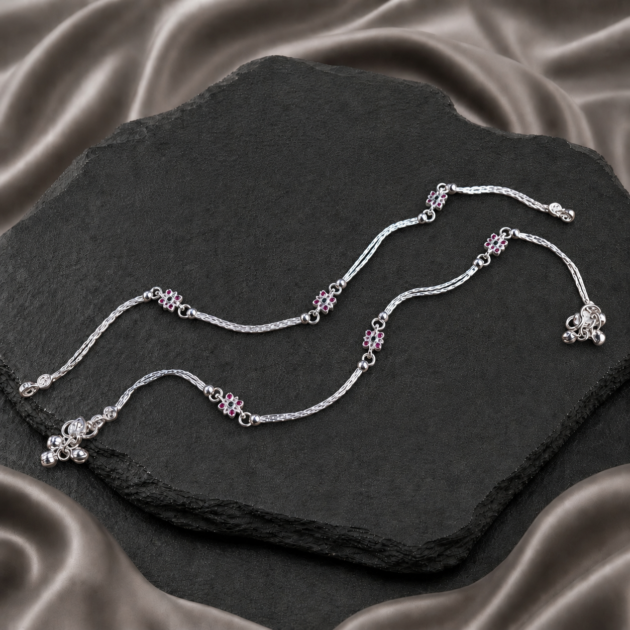 Pair of silver payals with pink floral accents and braided chains